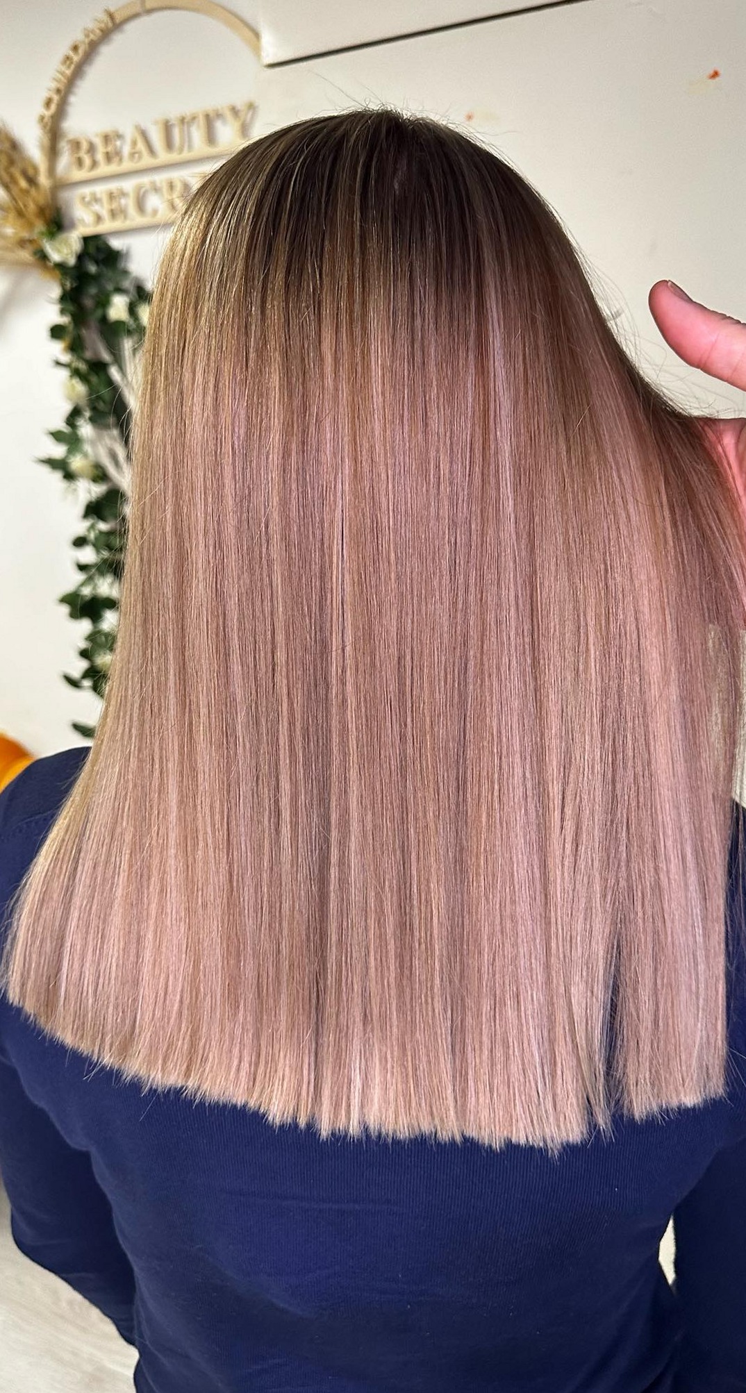 Roséblond haar van achteren, met het Beauty Secret bord erachter